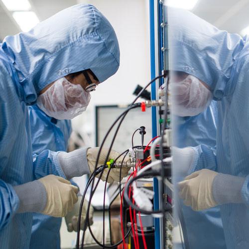 Image of a gowned, masked person working in a cleanroom environment